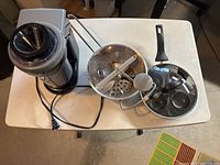 Photo of Starfrit electric spiralizer, metal food mill with crank, and black egg poacher with glass lid on table.