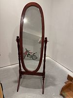 Front view of the full standing oval mirror with wooden frame and stand, showing overall condition and size.