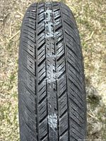 Close-up of the tire tread showing the directional pattern and size marking T125/80D16.