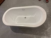 Top-down angled view of the white freestanding bathtub showing interior and crack on rim