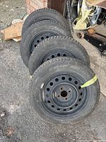 Four NTARES winter tires mounted on black steel rims standing upright, showing side profile including rim with holes.