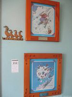 Photo showing two Gary Patterson framed prints on wall above and below, and brass duck key holder on left side.