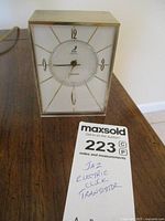 Full view of the vintage Jaz electric transistor clock with power cord showing, including MaxSold tag with lot details.