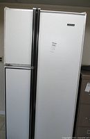 Front view of white Kelvinator side-by-side refrigerator with closed doors and vertical handles.