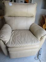 Front view of beige leather recliner showing padded backrest, seat and armrests