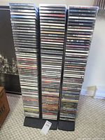Three tall stacks of rap and hip hop CDs in jewel cases on black metal racks
