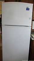 Front view of white Maytag refrigerator showing top freezer and larger refrigerator section below.