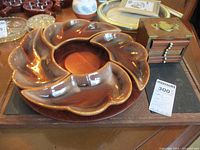 Brown glazed pottery Lazy Susan with swirl design and leaf-like compartments on a wooden table