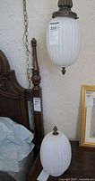 Hanging vintage ribbed globe light with chain beside a detached matching globe light sitting on surface, showing overall design and scale.