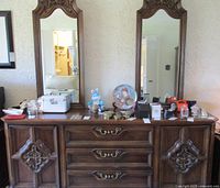 Front view of the oak dresser with two matching large mirrors above, showing drawer pulls, carved side cabinet doors and various items on top.