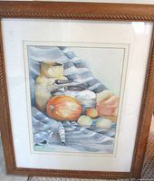 Full view of watercolor still life painting with fruits and vessels on striped cloth, framed in oak.