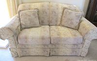 Front view of beige Whole Home love seat couch with patterned fabric and two cushions.