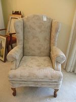 Front view of beige wing back chair showing cushioned seat, backrest, armrests, and upholstery pattern.