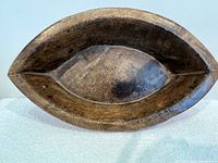 Top view showing the elongated oval shape of the thick wooden bowl, with a pointed end and visible wood grain.