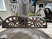 Front view of antique cast iron fireplace grate showing floral and scroll design and patina.