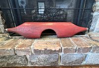 Full view of the small brick red wooden yolk placed on stone floor in front of fireplace.