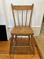 Full view of the antique wooden spindle back chair showing original finish and wooden seat, with 4 vertical spindles and sturdy legs