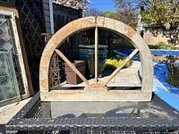 Photo showing entire antique wooden window frame placed on outdoor table with visible semi-circular design and geometric divisions.
