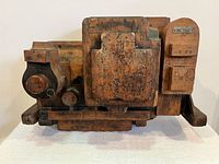 Frontal view of the large wooden factory mould showing rectangular base and various carved wooden parts with metal plates displaying numbers and letters.