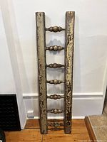 Full front view of antique wooden ladder section showing six turned rungs and weathered paint