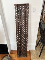 Full front view of tall rectangular wooden valance panel with many circular holes.