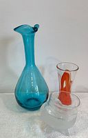 Overall group showing all three items together including the blue decanter, orange and clear drinking glass, and clear frosted vessel.