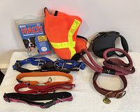 Photo showing the dog accessories including four collars, two leashes, blue walking harness, reflective dog vest, and new Halti headcollar in box.