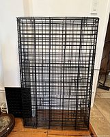Side view of the large black metal wire dog crate with plastic base and small door attachment.