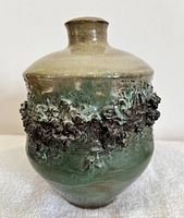 Front view of gilt lava pottery vase showing smooth glaze, lava texture band, and overall shape.