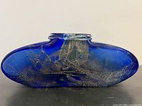 Side view of the deep blue blown glass vessel showing gold inlay and unique kidney-shaped form.