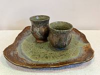 Front view of the handmade art pottery platter with two matching wine cups showing glazing, color, and shape.