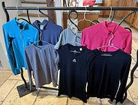 Full view of seven fitness shirts on hangers arranged on rack showing different styles and colors