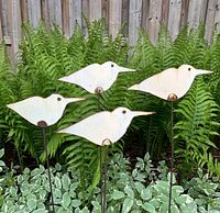 4 flat steel shore bird sculptures placed in garden plants showcasing size and arrangement.