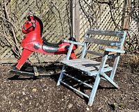 Photo showing both items outdoors on soil ground with wooden fence background. The red and black vintage rocking horse and light blue child's chair together.
