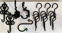 Top view showing all hooks laid out on a white surface, including the 12 screw-in hooks, 2 large ornate single hooks, 1 pair of double hooks, and one hand forged hook.
