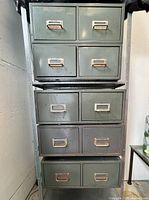 Full stacked view of four vintage metal filing cabinet units, showing four units stacked vertically with two drawers each, metal handles, label holders.