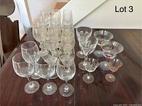 Set of 26 assorted wine and cocktail glasses in various sizes and styles arranged on a table.