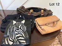 Photo showing four assorted bags: a large brown canvas duffel bag with leather accents at the back, a black gym/travel bag, a tan vintage leather briefcase-style bag with metal frame, and a black leather tote bag with a zebra design on the front.