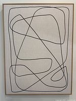 Front view of framed abstract line art print showing black linear design on neutral canvas within natural wood frame.