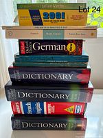 Stack of eleven language and reference books shown in clear daylight on a windowsill, titles visible.