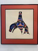 Full view of the framed Northwest Coast Indigenous art print depicting bold red, blue, and black stylized design.