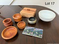 All items arranged together on a dark wood table showing wooden bowls, lidded box, ceramic bowl, metal bowl, and hummingbird coasters