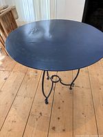 Full view of the round black metal table top showing surface texture and wear.