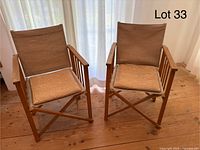 Pair of wooden folding director chairs with canvas seats, backs, and woven rush cushions on wood floor.