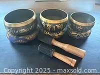 Three singing bowls of varying sizes with two wooden mallets.
