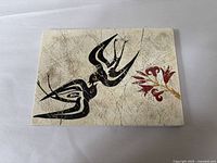 Photo showing the entire rectangular ceramic tile with two stylized swallows and red floral motif, crackled finish