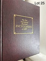 Close-up of a single volume showing the burgundy faux-leather cover with gold embossed title 'The New International Illustrated Encyclopedia of Art'.