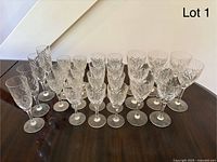 Photo of 27 vintage cut crystal wine glasses of different sizes arranged in rows on a surface with a consistent cut pattern.