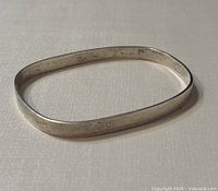 Birks Burkhardt 925 silver bangle on a light textured background, showing the rectangular shape and flat profile.