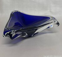 Top and angled side view showing deep blue inner glass with clear glass edges and smooth flowing triangular shape.
